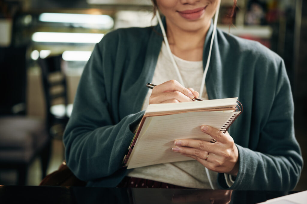 Close-up image of woman writing plans and ideas for video script
